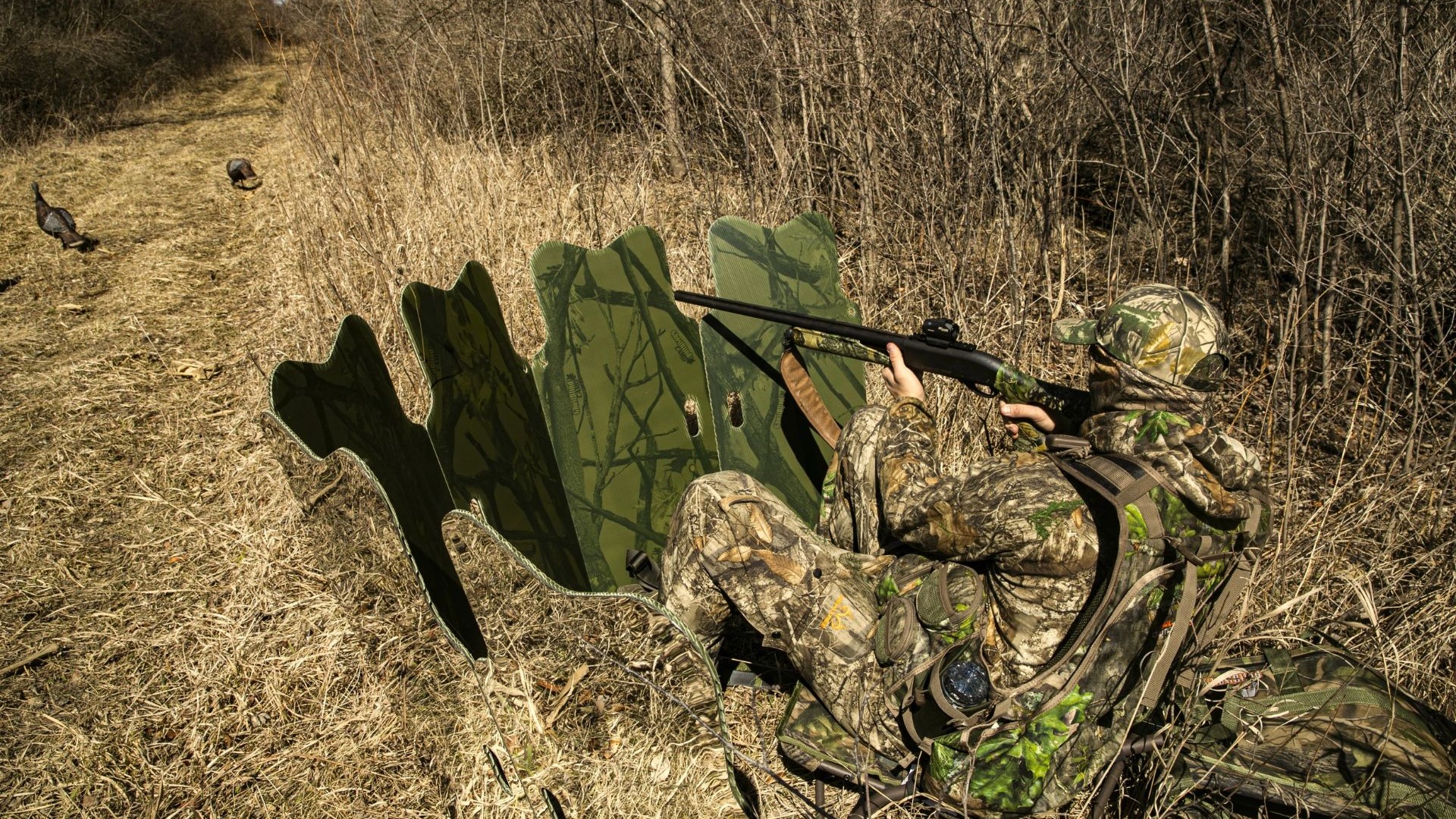 Hunter seated behind a GhostBlind mirrored blind during field setup