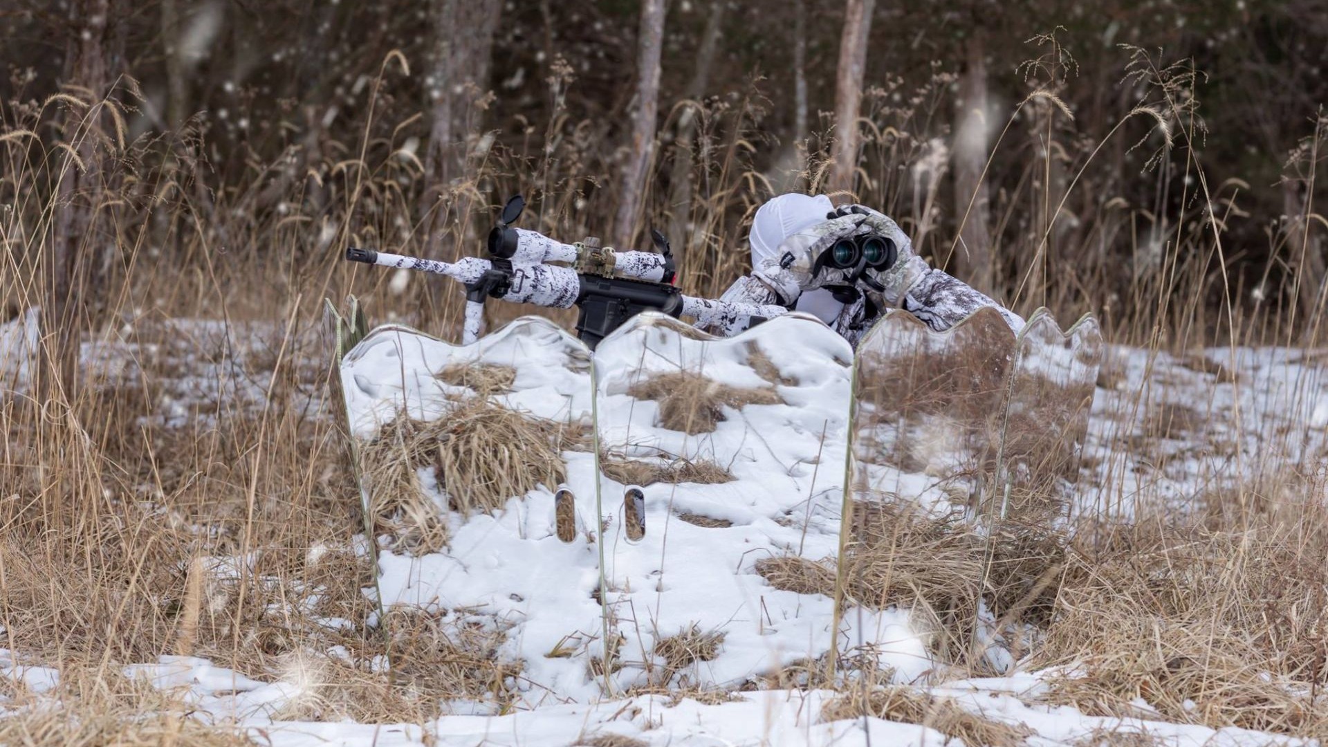 Hunter concealed behind a GhostBlind mirrored hunting blind in a snowy field